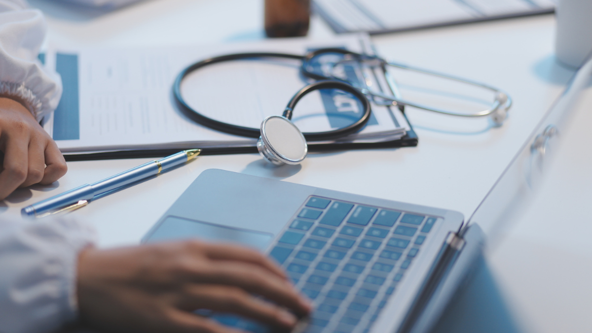 Laptop, stethoscope and clinical notes arranged on a virtual care workspace