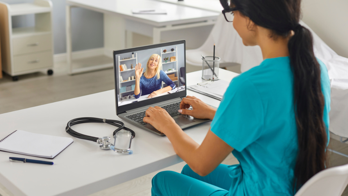 Clinician conducting virtual care consultation on laptop in medical office